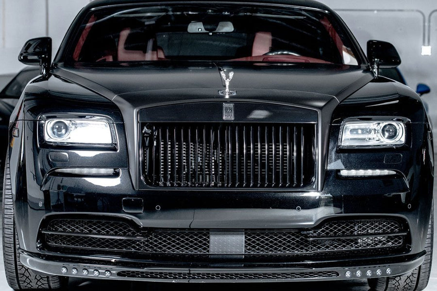 Luxury black sedan with prominent grille and distinctive emblem in a modern car showroom.