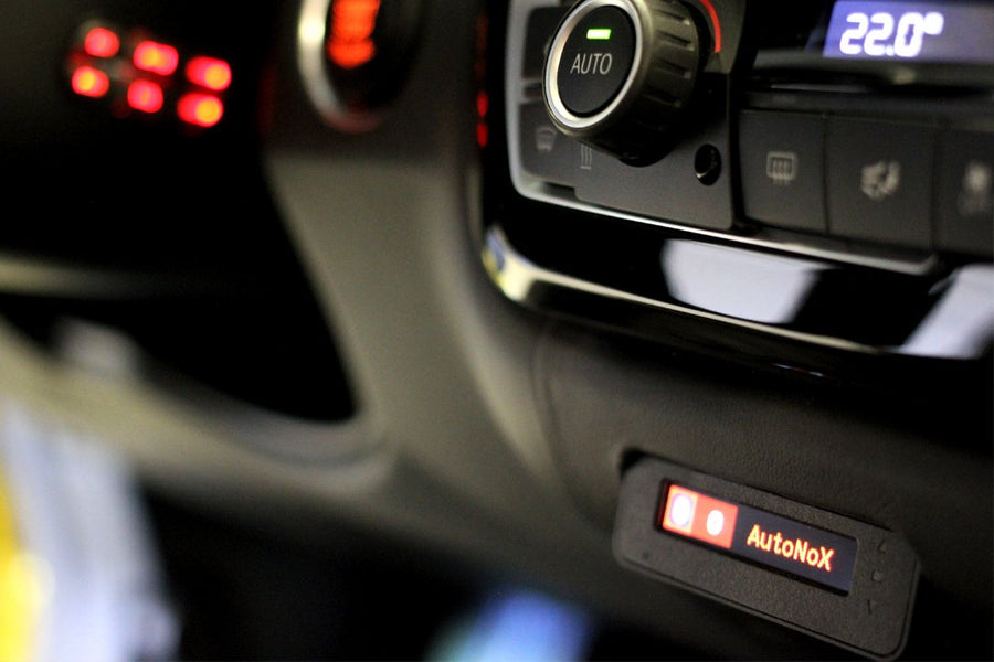 Close-up of a car's dashboard with AutoNox device and illuminated control buttons.