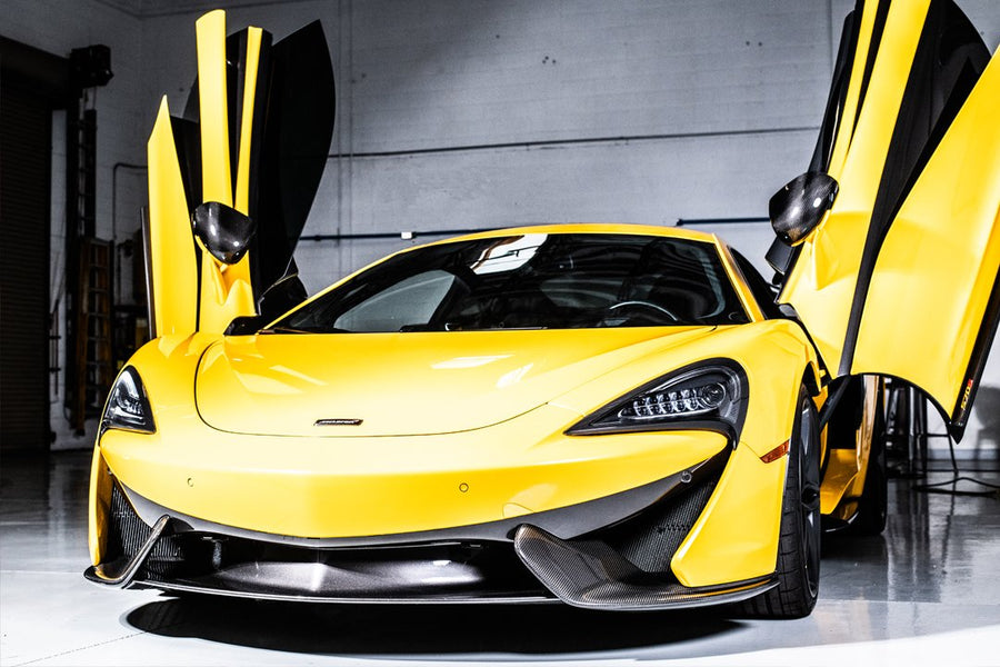 Yellow sports car with butterfly doors open inside a garage.