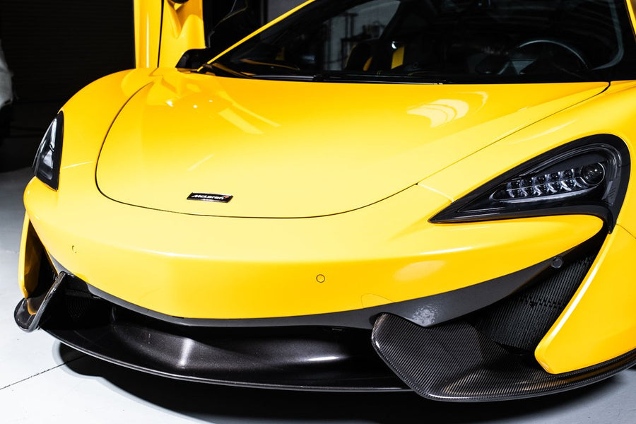 Close-up of a sleek yellow sports car with black accents in a showroom.